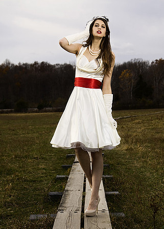 Fashion photography of woman in classic white dress on board walk in field